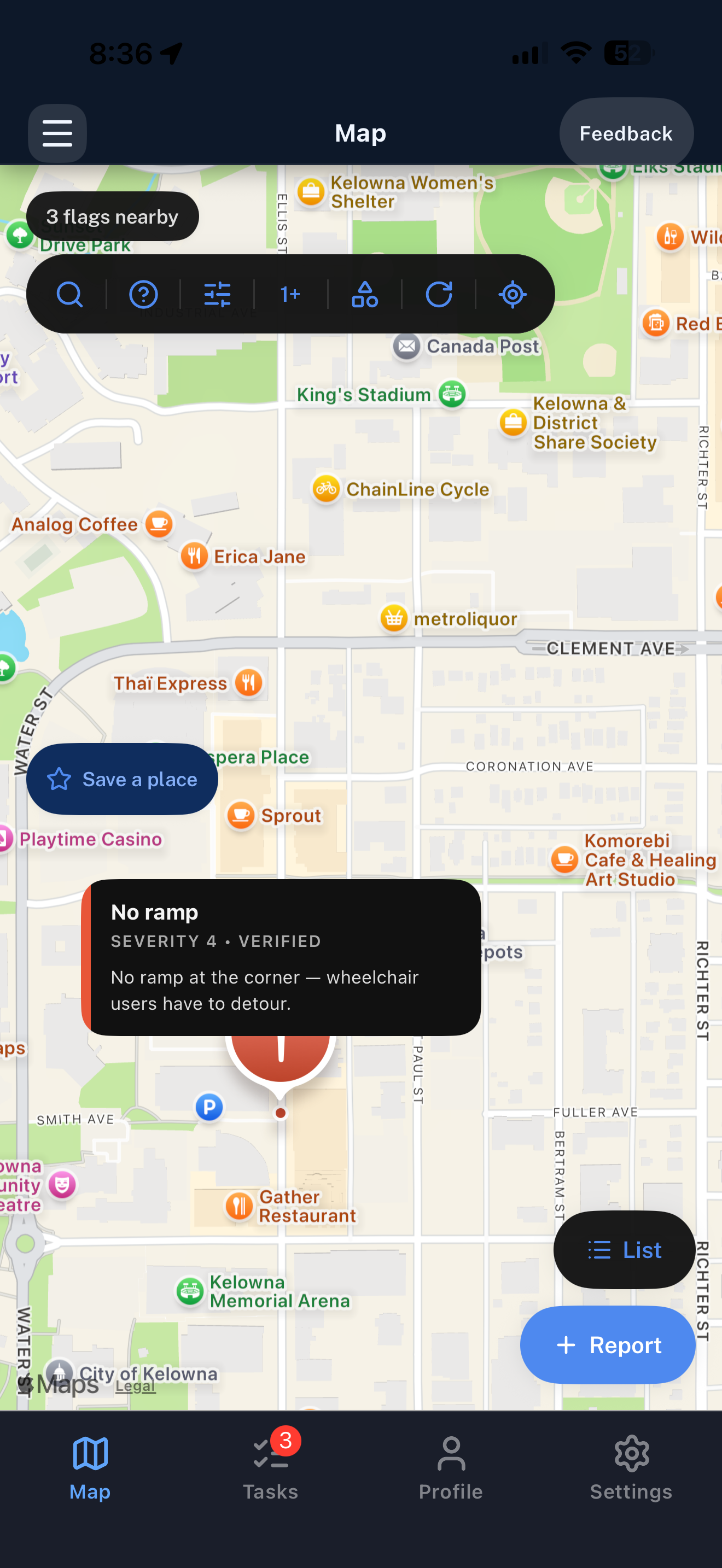 AccessMap's map view with a barrier pinned to a downtown Kelowna corner, three nearby flags, and a Report button